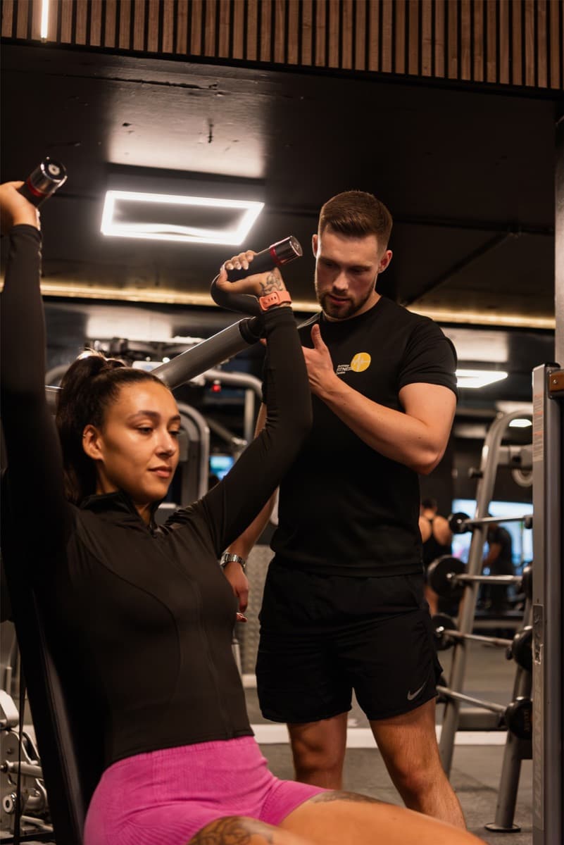 An Avoya coach guiding a member through a press, both focused and smiling
