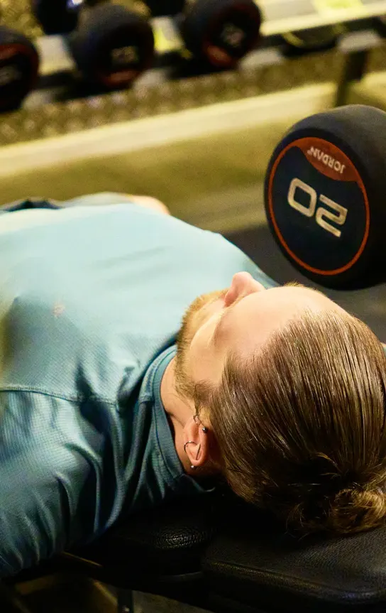 Overhead view of a member pressing dumbbells on the bench
