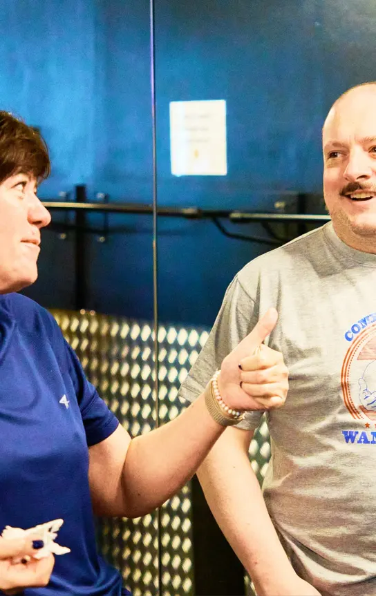 Two members laughing together during a training session on the gym floor