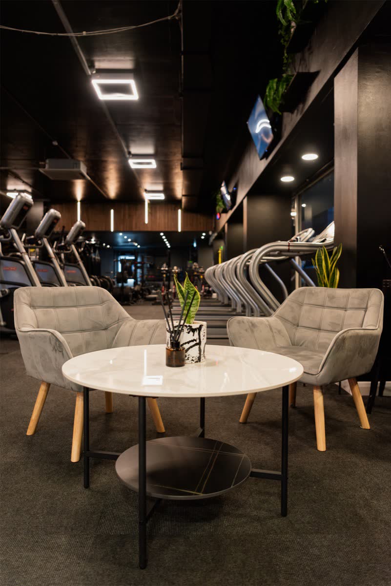 The lounge area: armchairs, tables and planting beside the cardio zone