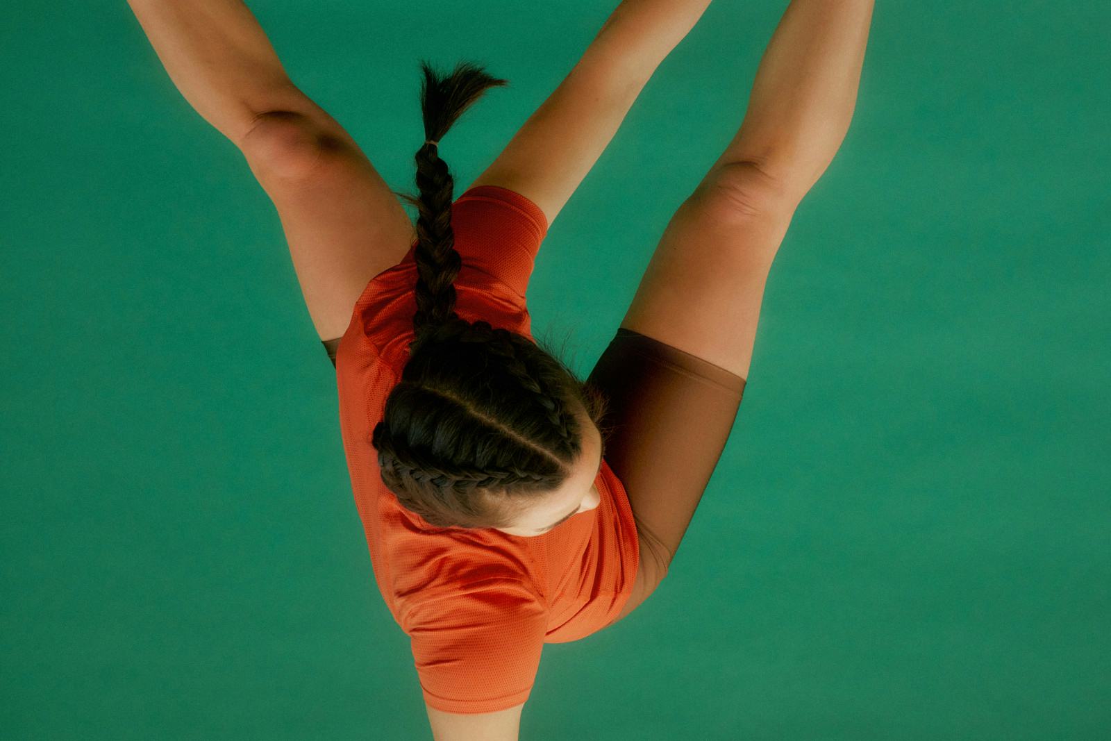 A member folding into a deep stretch, seen from above against a green floor