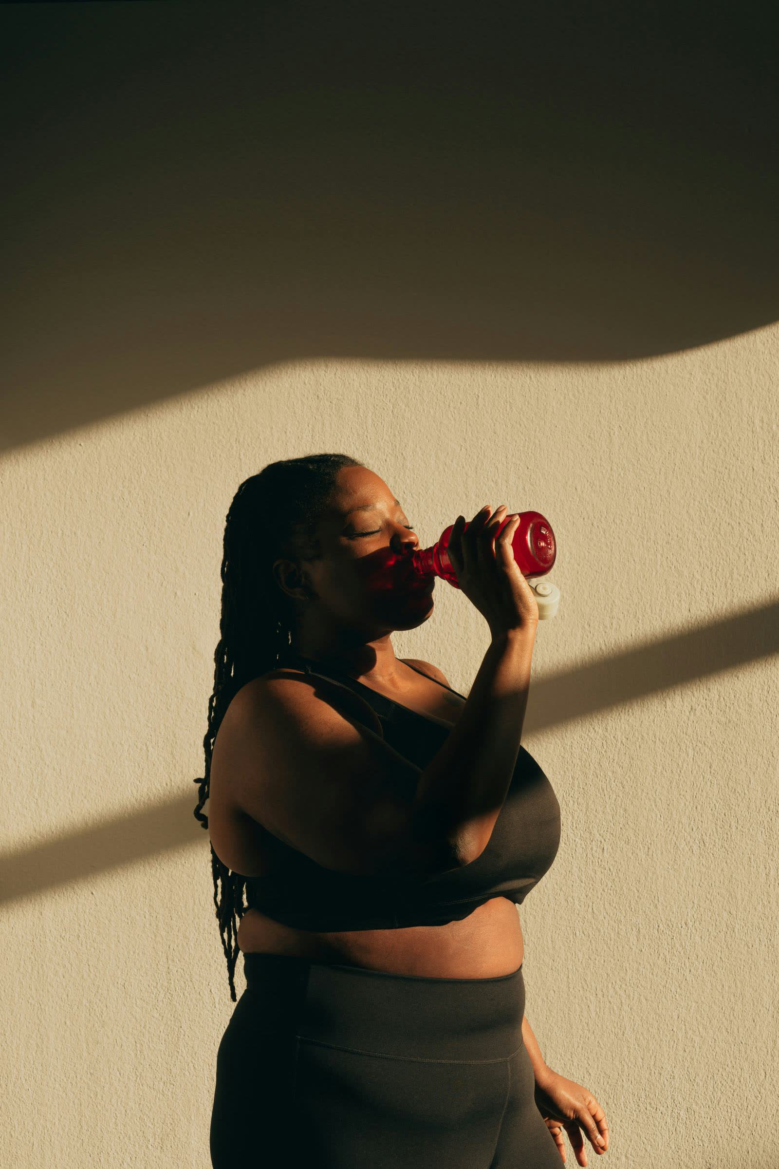A member rehydrating in warm evening light, eyes closed, the recovery mindset