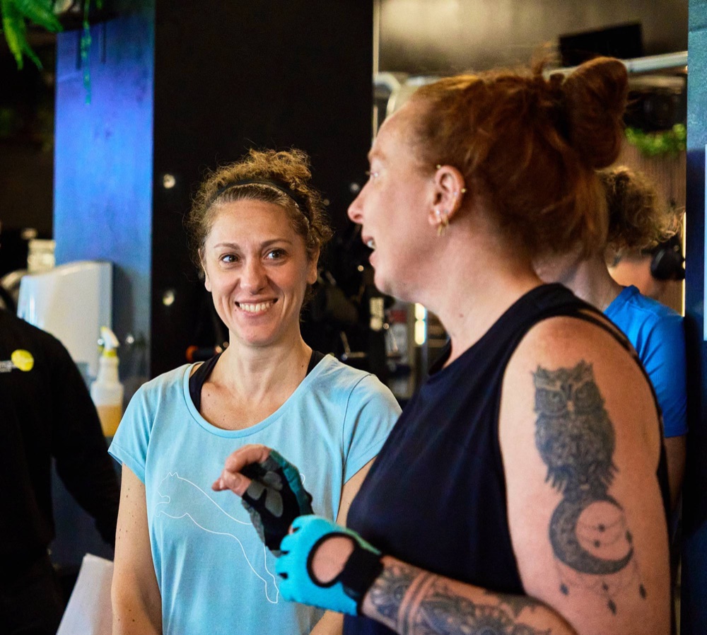 Two Avoya members smiling and chatting in the gym