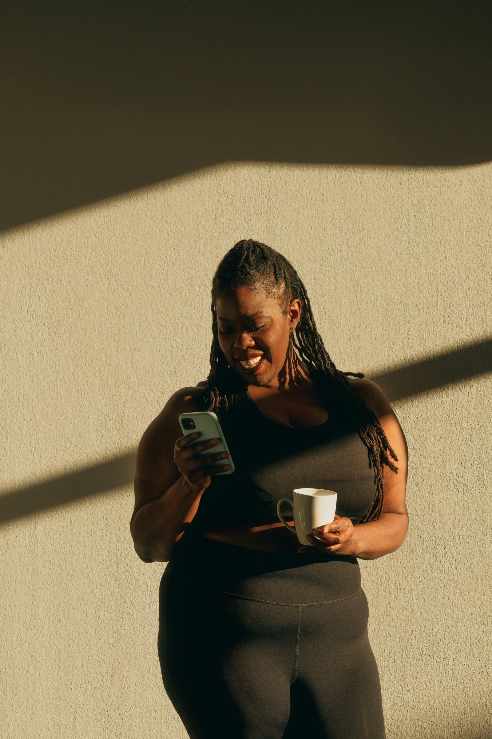 Member smiling at their phone during a check-in, coffee in hand
